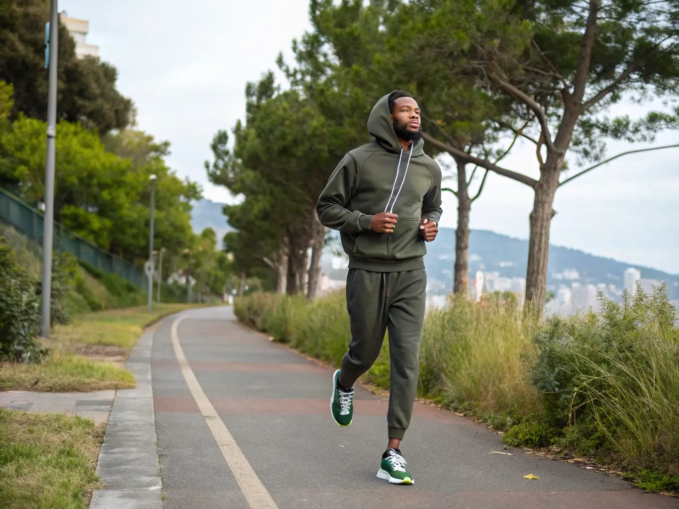 A young person walking in the city wearing joggers and a hoodie, showcasing versatile style and comfort. The background is a vibrant urban street.